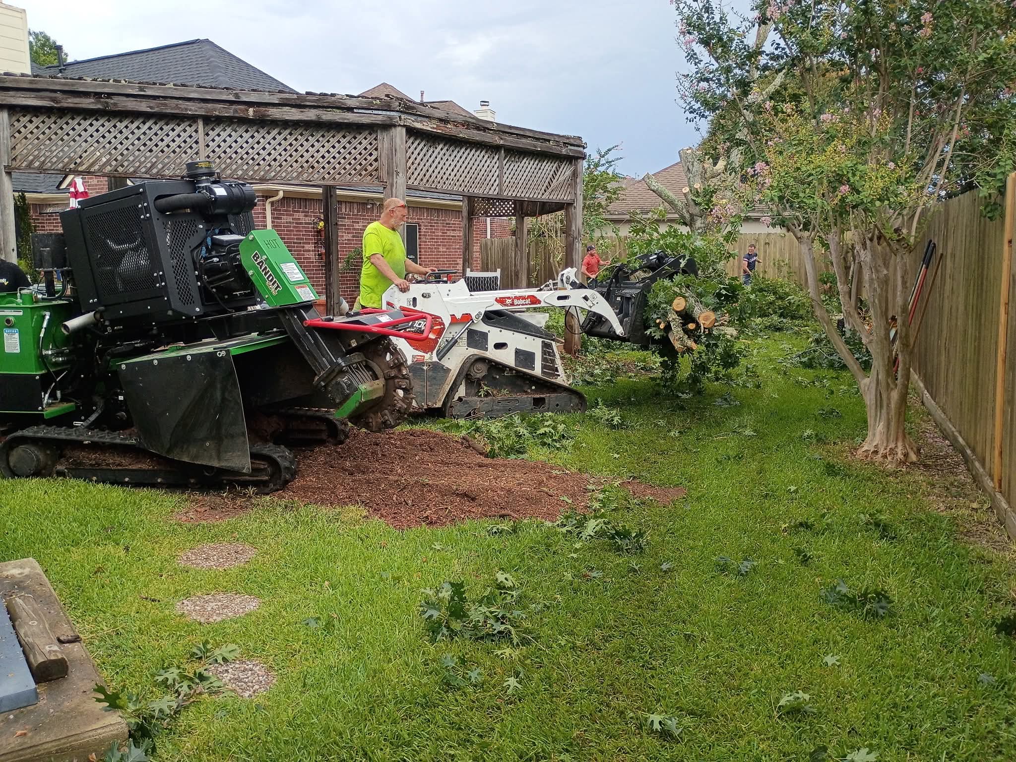 Bandit stump grinder and Bobcat skid-steer in Houston backyard